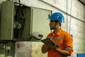 A maintenance worker inspecting an electrical box using mpro5 on a tablet