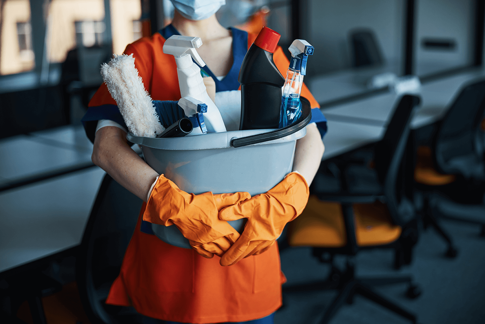 a closeup shot of a cleaner holding a bucket of cleaning supplies