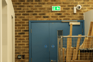 a fire exit blocked by a roller cage full of old wood