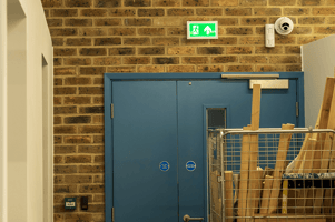 a fire exit blocked by a roller cage full of old wood