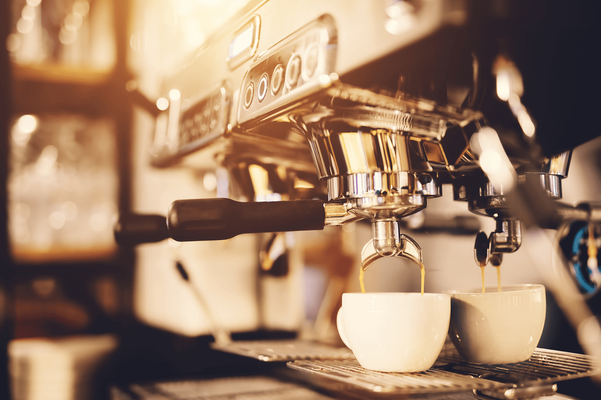 two coffees being poured on a coffee machine