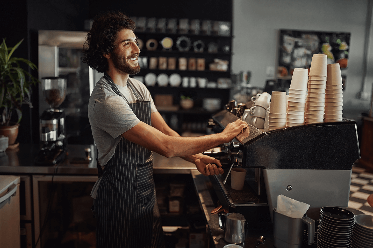 A happy barista making a coffee in a neat coffee shop