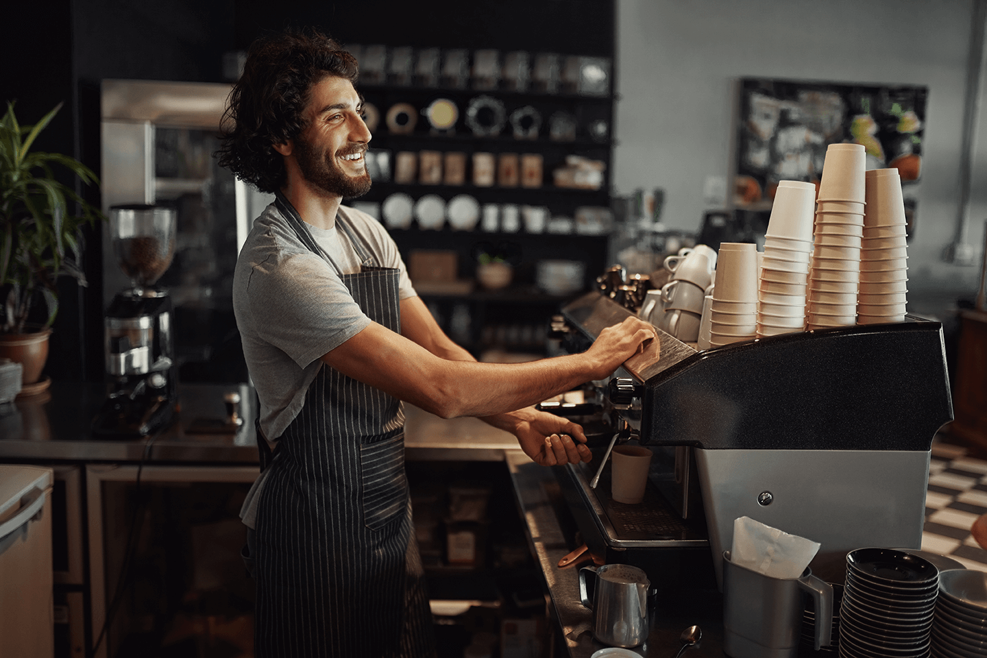 A happy barista making a coffee in a neat coffee shop A happy barista making a coffee in a neat coffee shop