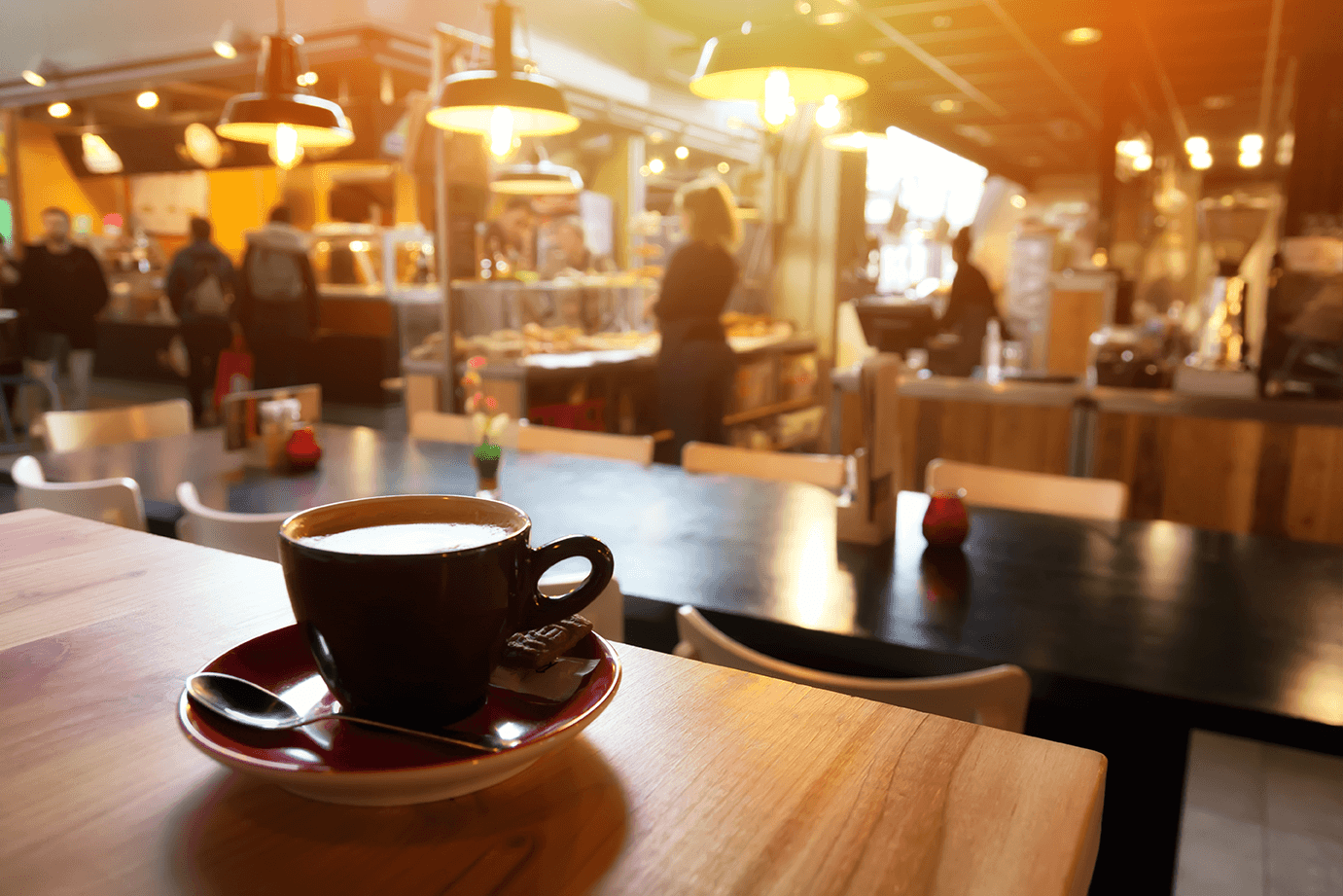 a cup of coffee on a table in a busy cafe